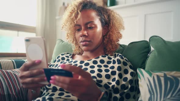 African American Woman Holds Phone and Dials Contact Number with Business Card