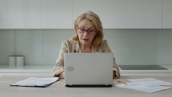 Happy Elderly Woman with Glasses and Looking at the Camera at Home