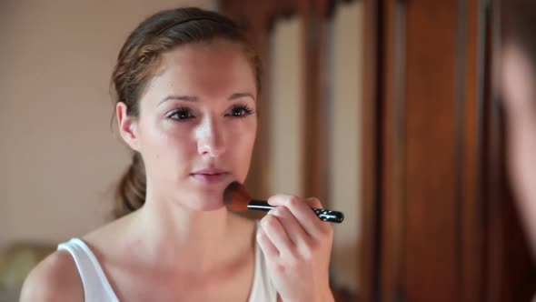 Beautiful Woman at the Mirror Applying Make Up