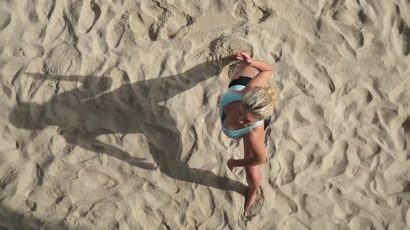 Overhead shot of a young attractive woman doing yoga on the beach