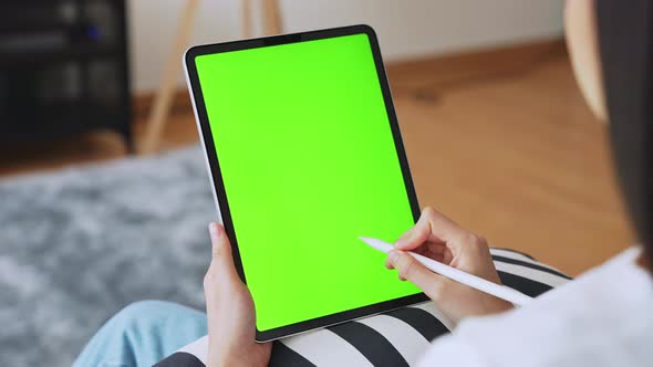 Woman holding in hands a digital tablet with green screen for internet online.