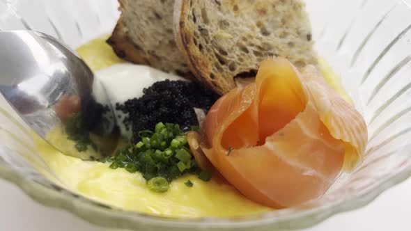 Closeup of a Man Scooping a Black Caviar and Scrambled Salmon Omelet with Steel Spoon From