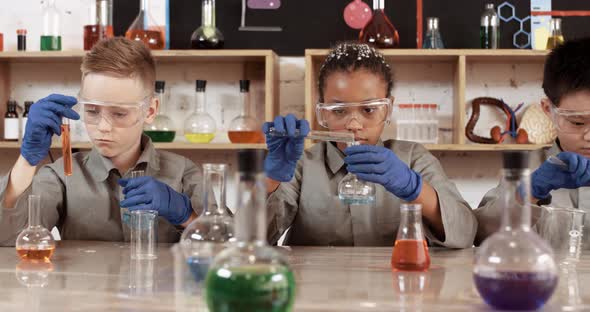 Laboratory Experience in a Chemistry Lesson, Kids in Protective Glasses Pours a Liquids Into a