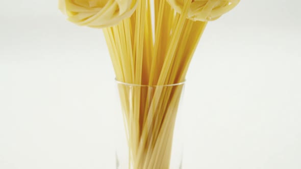 Spaghetti arranged in flower shaped on white background in glass jar