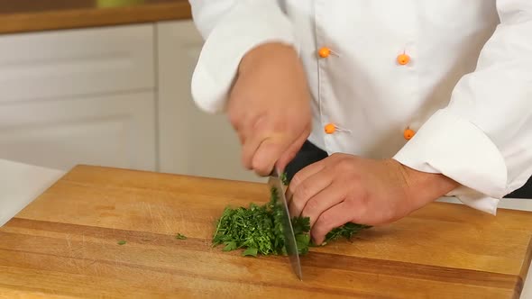 Cutting Parsley and Dill with a Knife on Wooden Board