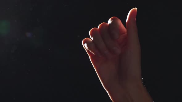 Silhouette Portrait of Elegant Female Hand Closeup Raised Upward and Playing in Light with Flying