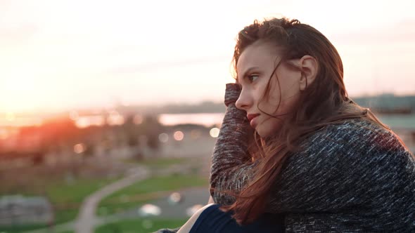 Portrait of Beautiful Sad European Young Woman on Roof or Balcony or Terrace Enjoying Sunset