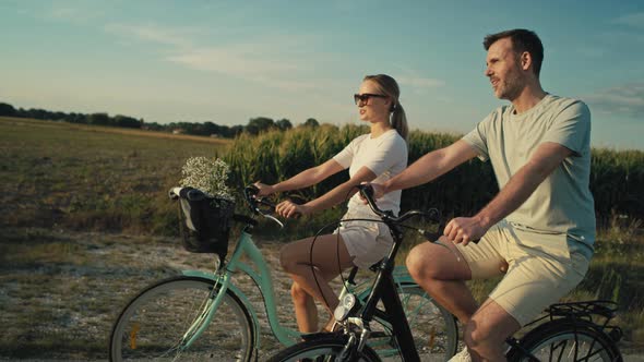 Side view of playful caucasian couple having fun while riding a bike on village road. Shot with RED