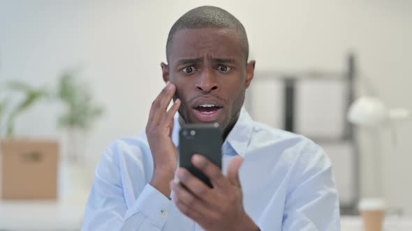 African Man Loss on Smartphone in Office