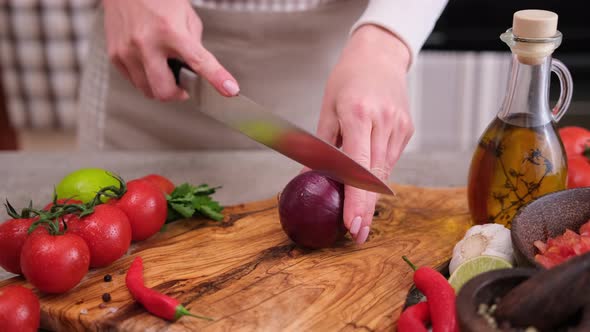 Woman Chopping Red Onion on Wooden Board at Domestic Kitchen