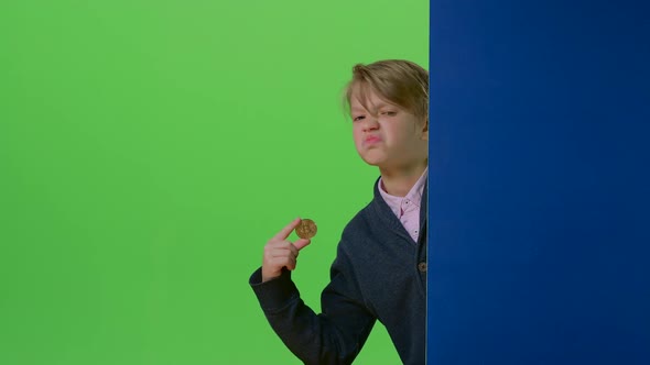 Teenager Peeks Out From Behind a Board Shows the Coin and Dislike on a Green Screen