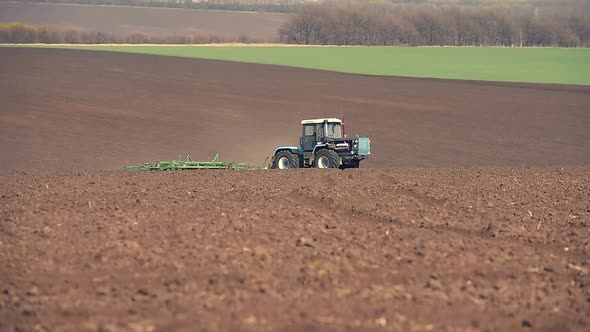 A Tractor Plowing and Sowing in the Field