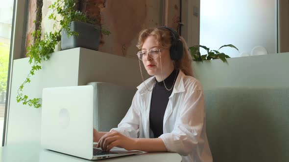 A Young Girl Works Remotely in a Cafe on a Summer Terrace