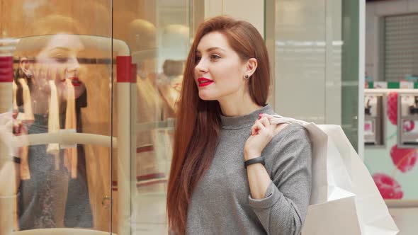 Attractive Woman Enjoying Shopping at the Mall, Examining Clothes on Display