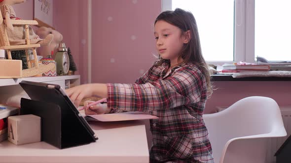 Distance education at home, online e-learning. Cute child is looking in laptop screen lying on bed 