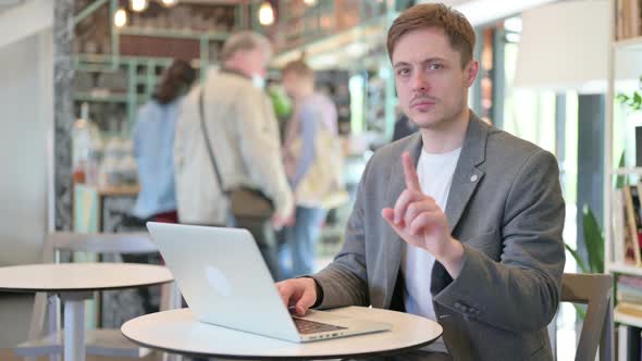 No Gesture with Finger By Young Man in Cafe