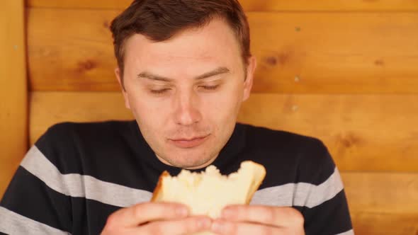 a Man Bites and Eats a Sandwich Made of White Bread