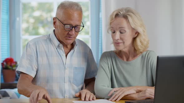 Senior Couple at Home Discuss Income and Pay Bills Online Scanning Qr-code