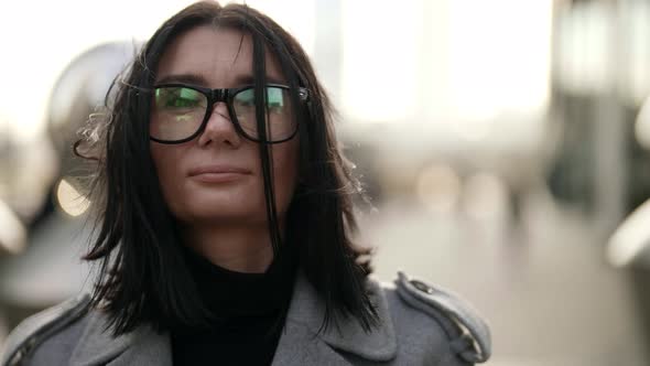 Portrait of a Brunette with Glasses on a Background of Blurred Metal Structures
