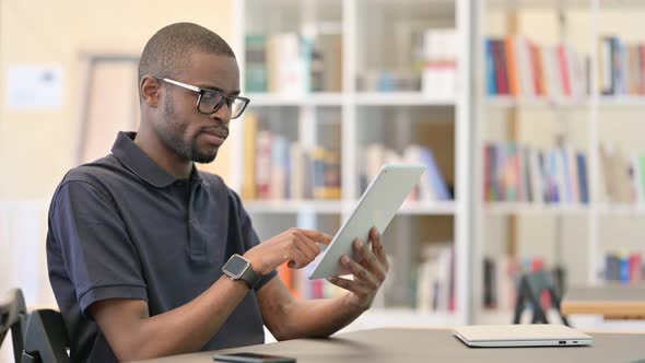 Professional Young African Man Using Tablet in Library