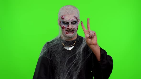 Halloween Zombie Man Bloody Makeup Showing Victory Sign Hoping for Success and Win Peace Gesture