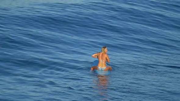 A young woman surfing in a bikini on a longboard surfboard.