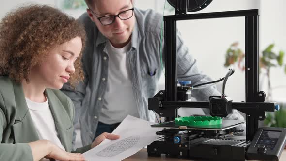 Smiling Woman with a Man Uses Modern Technology and Happily Watches a 3D Printer at Home While