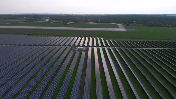 Drone Slow Flies Into Large Solar Panels at a Solar Farm at Cloudy Summer Evening. Solar Cell Power