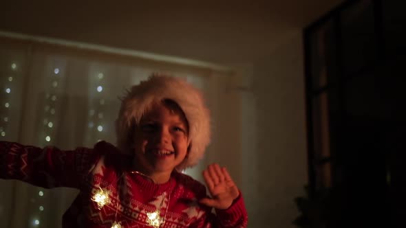 Excited Christmas Boy Dancing in Santa Hat at Home Evening