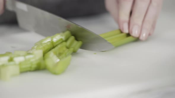 Curring vegetables on a white cutting board to cook vegetarian white bean soup.