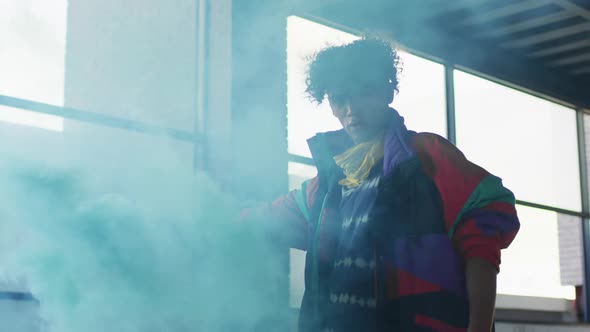 Mixed race man holding blue flare standing in an empty building