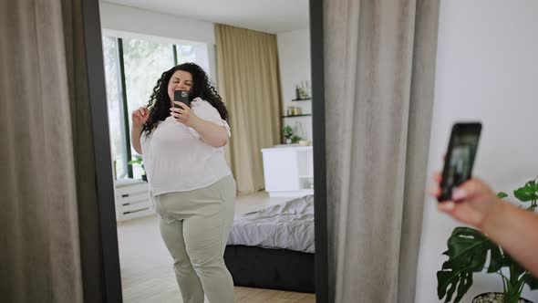 Young Overweight Woman Dances Looking at Mirror Reflection