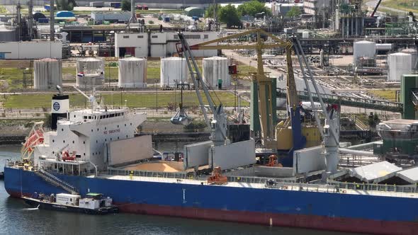 Bulk Carrier Ship at Port Offloading Cargo and Commodities by Shore Crane