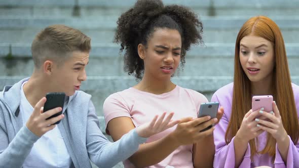 African-American Girl Displeased With Bad Photo Comment Showing Phone to Friends