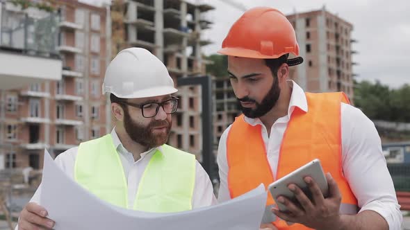 Building a Residential Complex or Business Center. Team of Engineers Men with a Tablet and Drawing