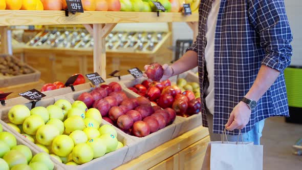 Greengrocery Customer with Paper Bag Buying Apples