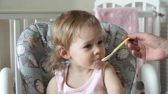 Fathers Hand Feeds Little Baby Girl From Spoon Yogurt