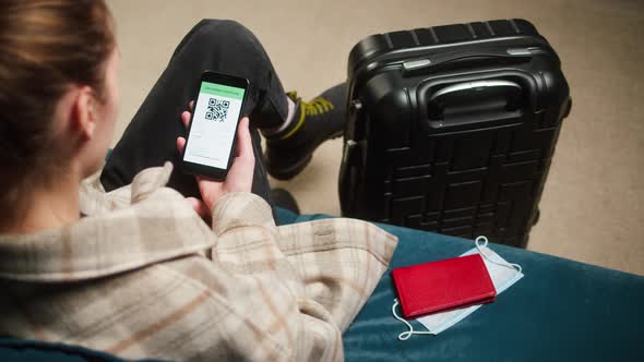 Woman Tourist Holding QR Code on Phone Sitting in Airport Terminal