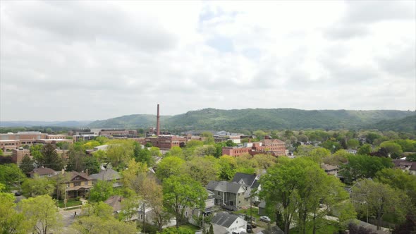 Aerial view over midwest city in valley with bluffs and cloudy sky in the distance.