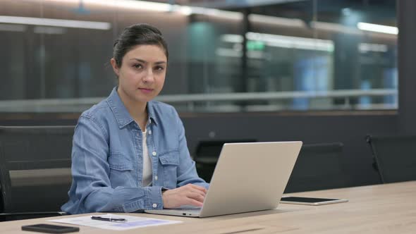 Indian Woman Looking at Camera While Using Laptop