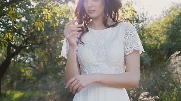 Young beautiful woman in white dress and brown hat posing. Attractive fashion model with loose hair.