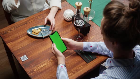 Woman Using Smartphone with Chroma Green Screen Online Menu in Cafe