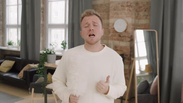 Young Man Singing into Dust Brush at Home