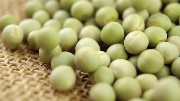 Dry green peas. Falling dried legumes on a rustic sackcloth. Macro