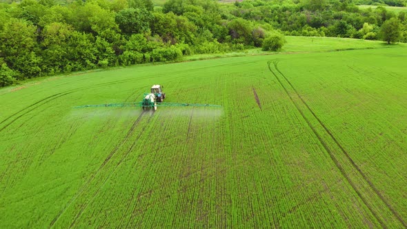 Aerial View of Farming Tractor Spraying on Field with Sprayer Herbicides and Pesticides at Sunset