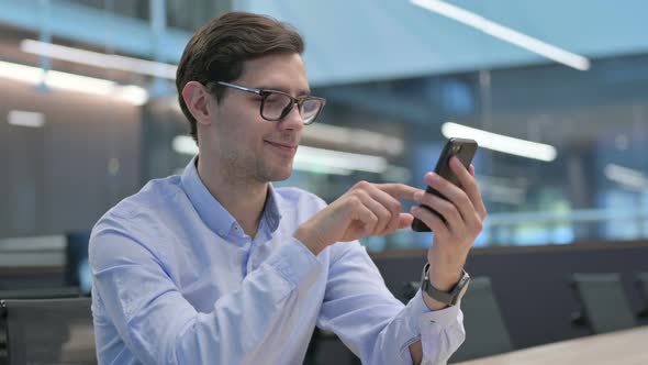 Young Man Celebrating Success on Smartphone