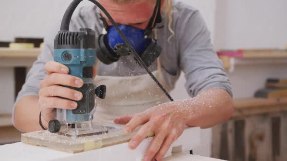 Caucasian male surfboard maker wearing a face mask and making a surfboard