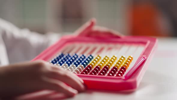 Little Girl Hand Adjusts Toy Abacus Moving Small Beads