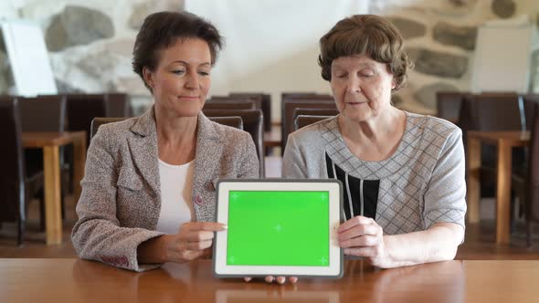 Happy Mother And Daughter Showing Digital Tablet Together At The Coffee Shop