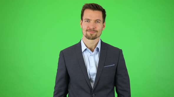 A Young Handsome Businessman Holds a Picture in Front of Himself, He Enlarges It with His Fingers